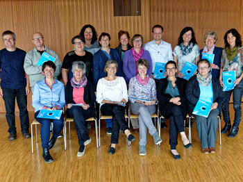 Eine Zertifikatsverleihung von Hospiz Vorarlberg. Sie sitzen und stehen für ein Gruppenfoto zusammen. 