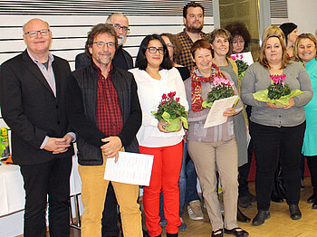 Gruppenfoto der Sozialpaten mit Peter Klinger. Sie alle sind modisch schick angezogen in ganz unterschiedlichen Farben. Manche Personen haben Blumen in den Händen. 