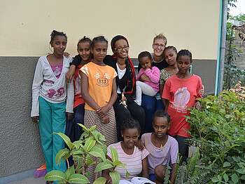 Gruppenfoto vor dem Girlshostel in Ähtiopien. Mädchen und junge Frauen posieren vor dem Hostel im Garten. Sie sind bunt in allen Farben gekleidet. 