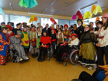 Großes Gruppenbild der Klienten und Mitarbeiter der Werkstätte Bludenz im Fasching. Alle sind verkleidet. 