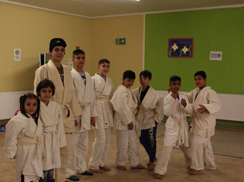 Die Flüchtlingskinder beim Judotraining. Alle tragen eine weiße Judouniform und stehen in einer Reihe. Manche schon in einer Judostellung. 